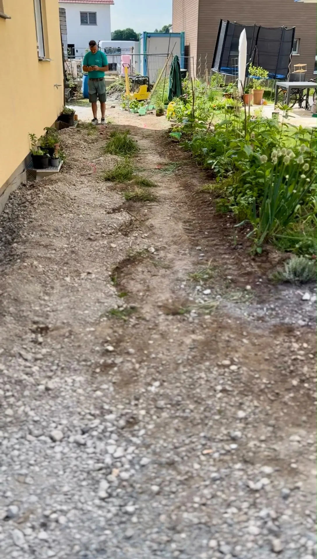 Unbefestigter Erd- und Schotterstreifen neben dem Haus vor dem Wegebau