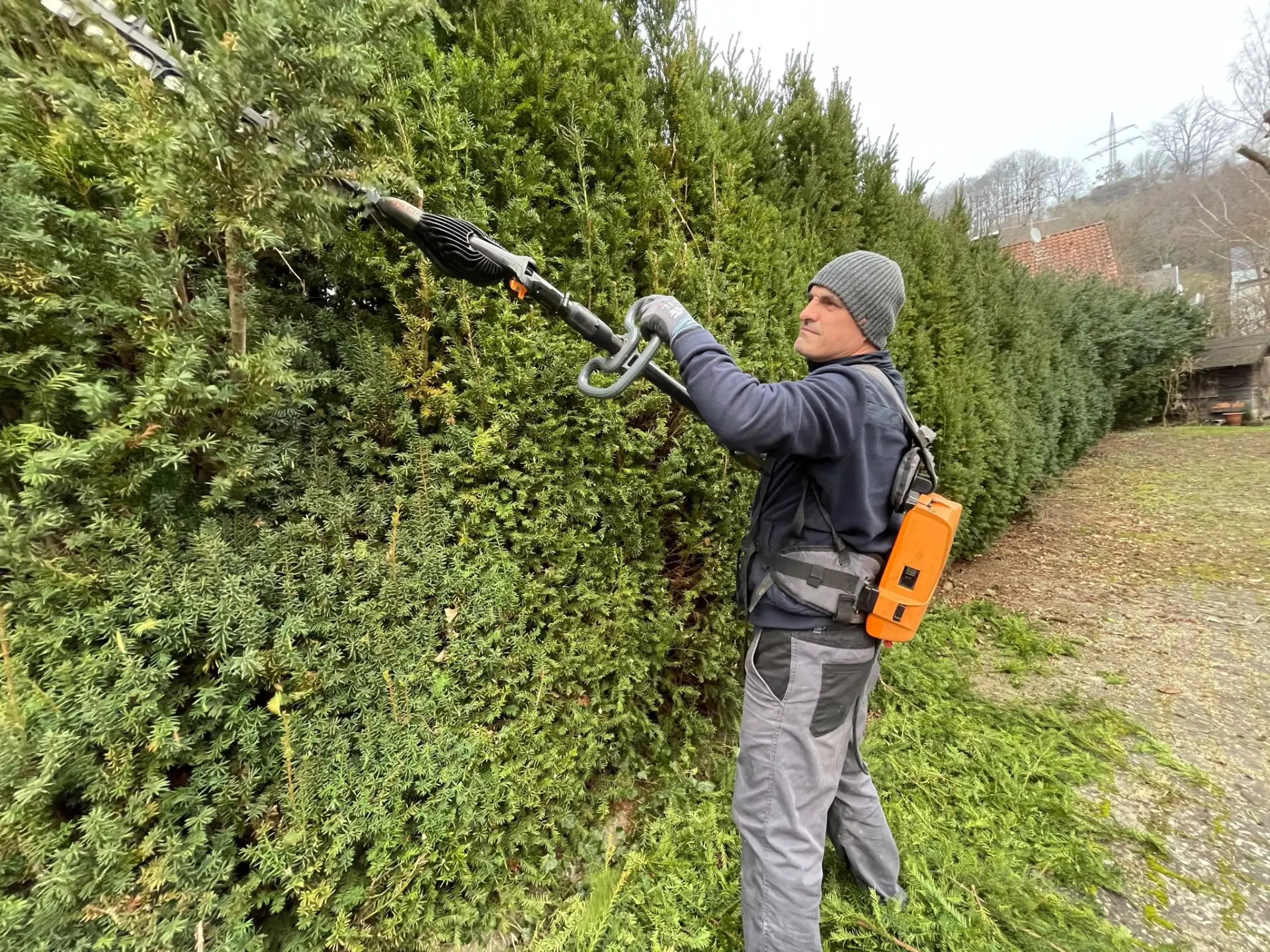 Mitarbeiter von Shukaj Gartenbau beim Heckenschnitt mit der Teleskop-Heckenschere