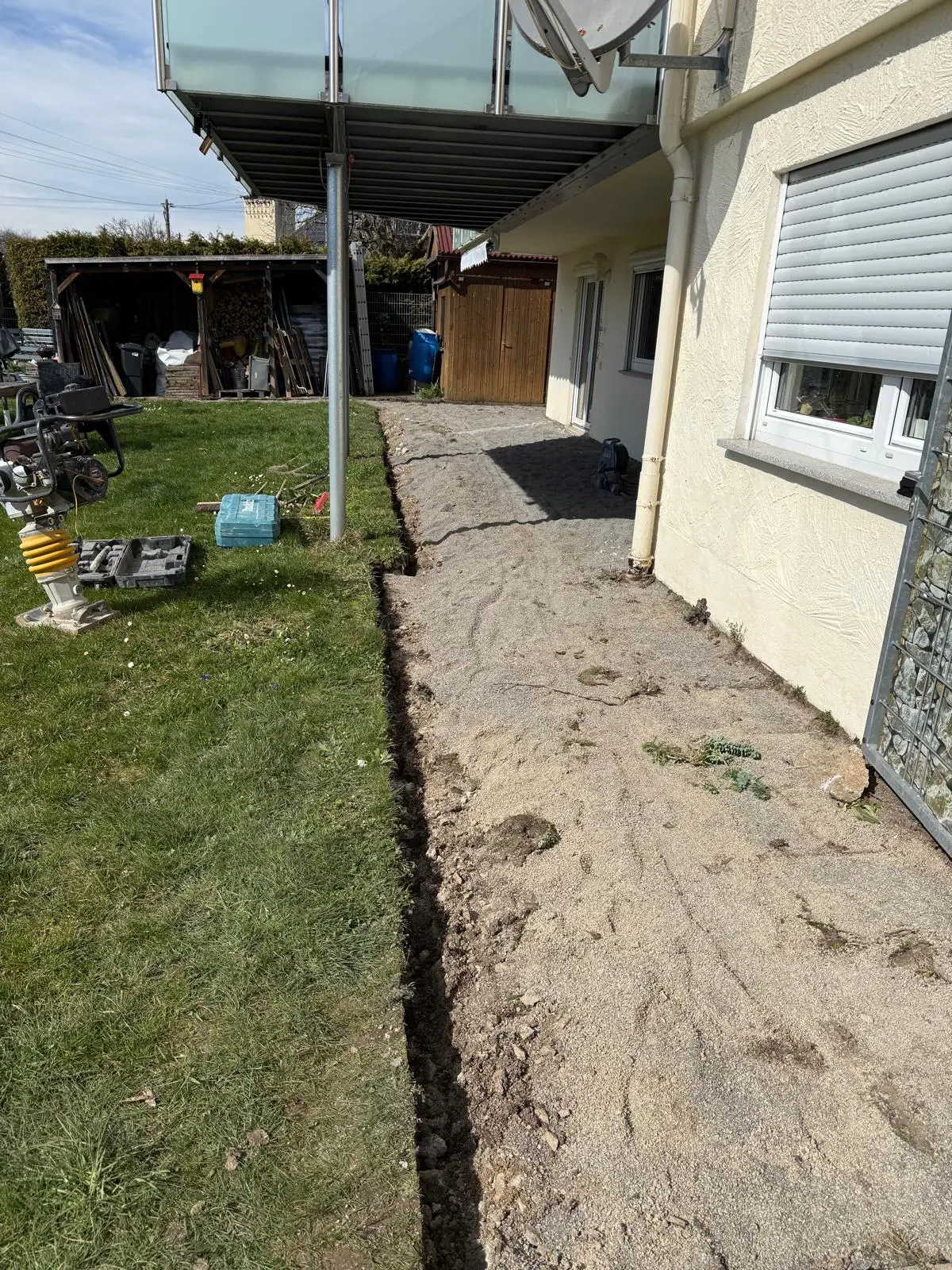 Abgetragene Terrassenfläche mit vorbereitetem Unterbau und Rüttelplatte