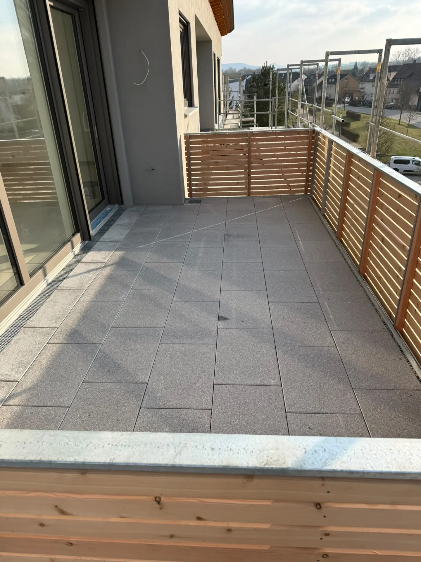 Fertiger Balkon mit grauen Betonplatten und Holzverkleidung der Brüstung