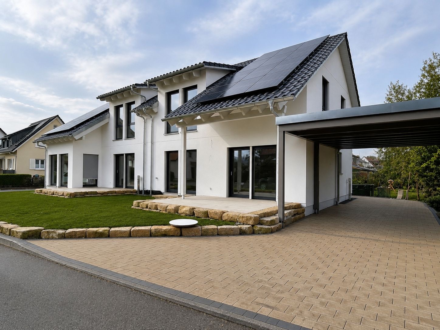 Neu angelegter Hausgarten mit Rasenfläche, Sandstein-Randsteinen, Terrasse und gepflasterter Einfahrt